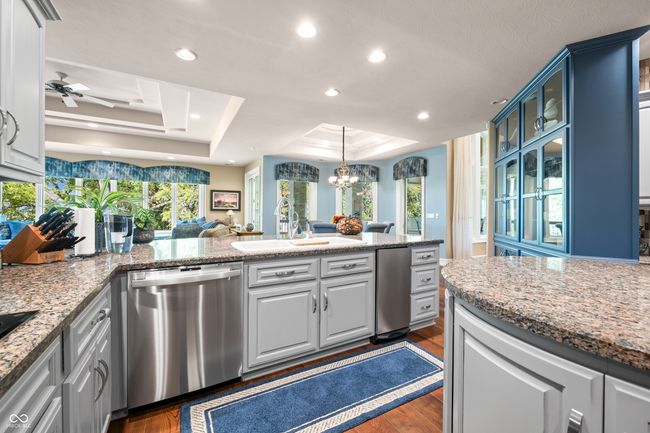kitchen featuring dark wood-type flooring, a raised ceiling, stainless steel dishwasher, and a sink | Image 31