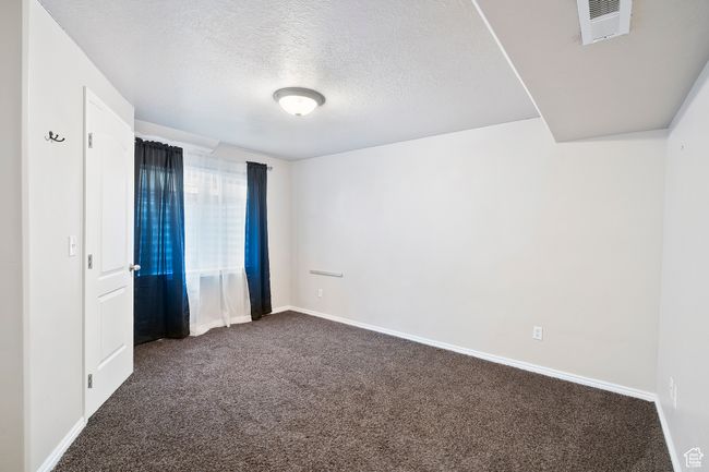 Unfurnished room featuring dark colored carpet and a textured ceiling | Image 24