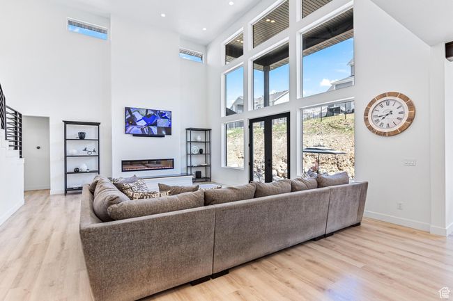 Living room with wood finished floors, a towering ceiling, baseboards, and recessed lighting | Image 17