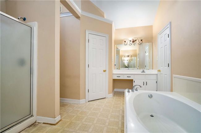 Bathroom featuring a garden tub, a stall shower, vanity, a chandelier, and tile patterned floors | Image 19