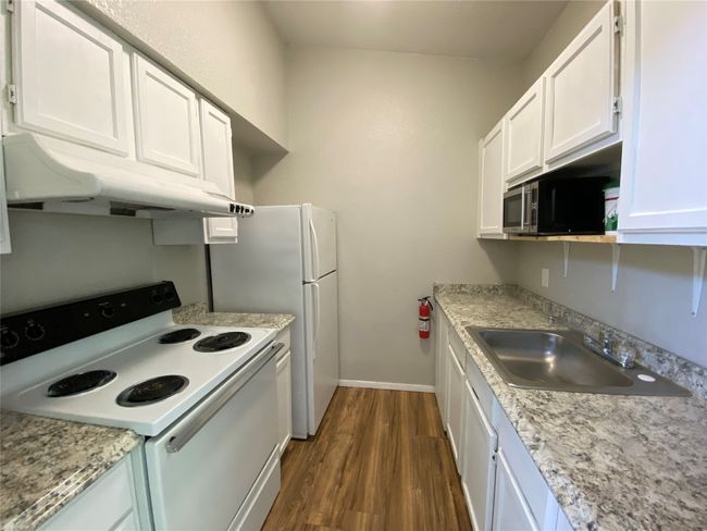 Super clean kitchen with brand new countertops and plenty of storage space. Notice the white appliances and cabinets. | Image 6