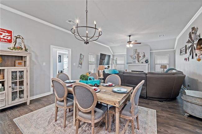 Dining space featuring crown molding, dark wood-style floors, visible vents, and ceiling fan with notable chandelier | Image 17