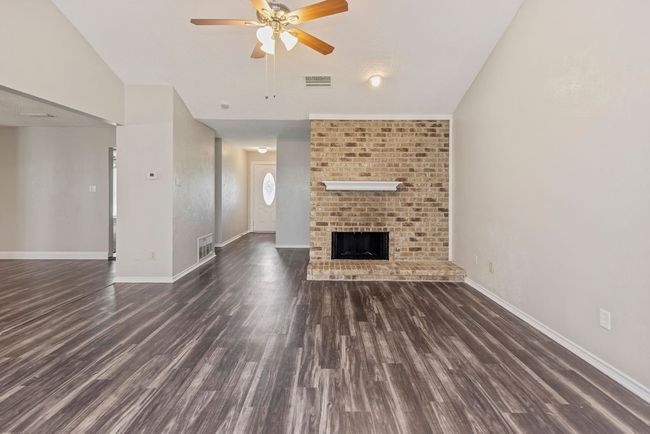Unfurnished living room featuring ceiling fan, wood finished floors, baseboards, and a fireplace | Image 6