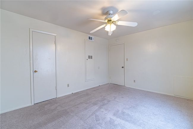 Empty room with a ceiling fan, light carpet, and baseboards | Image 9