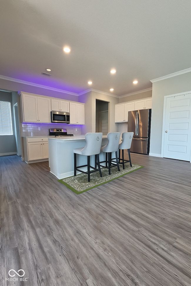 kitchen featuring stainless steel appliances, crown molding, white cabinets, baseboards, and dark wood-type flooring | Image 7