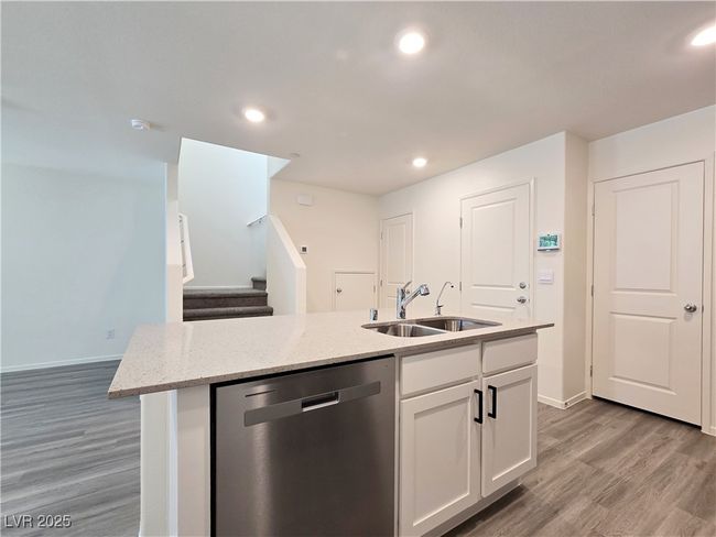 Kitchen with stainless steel dishwasher, a sink, light wood finished floors, a kitchen island with sink, and white​​‌​​​​‌​​‌‌​‌‌​​​‌‌​​‌‌​‌​​​​​‌ cabinets | Image 13