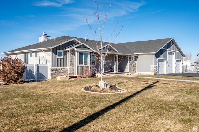 View of front facade featuring a front yard, stone siding, board and batten siding, fence, and a gate | Image 4