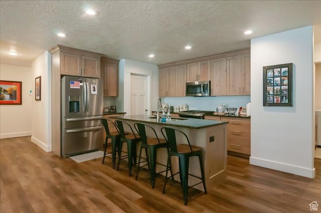 Kitchen featuring appliances with stainless steel finishes, dark countertops, a sink, dark wood-style flooring, and baseboards | Image 6