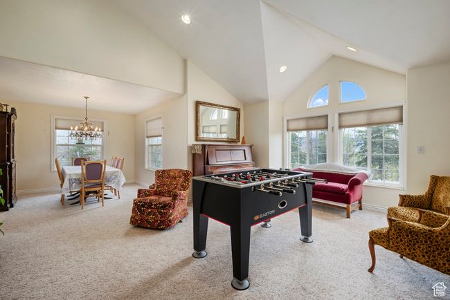 Recreation room with baseboards, a notable chandelier, a healthy amount of sunlight, and carpet | Image 11
