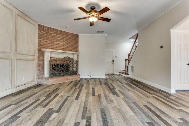 Unfurnished living room with visible vents, ornamental molding, a fireplace, and stairway | Image 7