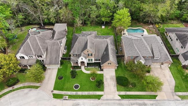 This stunning aerial perspective showcases the home’s ideal placement on a spacious lot with lush landscaping and greenbelt privacy. Nestled among mature trees with no back neighbors, it offers peace, space, and excellent curb appeal in a desirable neighborhood. | Image 40