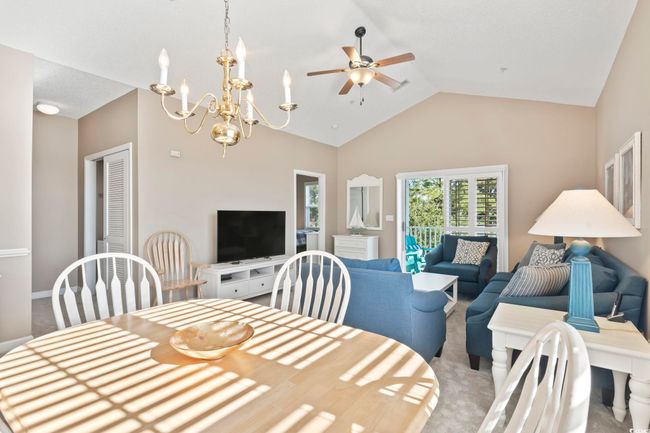 Dining area featuring ceiling fan, high vaulted ceiling, carpet floors, and a chandelier | Image 14