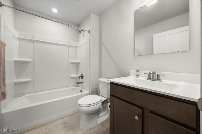 Full bathroom with toilet, tile patterned floors, bathing tub / shower combination, and vanity | Image 10