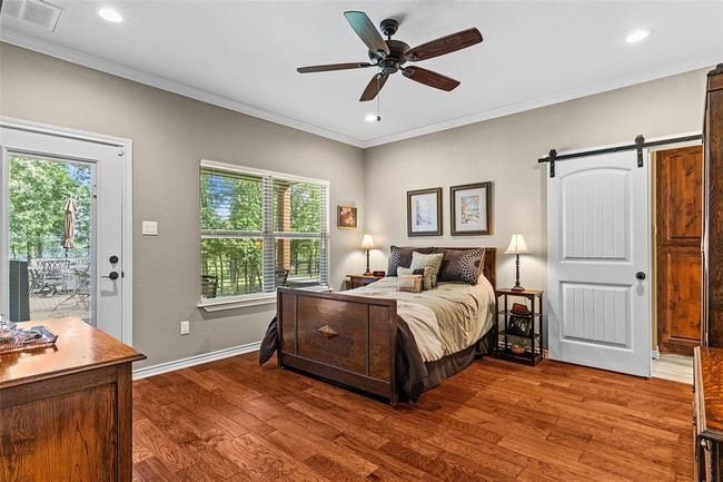 Bedroom with a barn door, ceiling fan, hardwood / wood-style floors, and multiple windows | Image 14