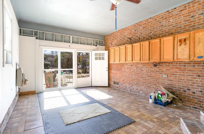 Interior space with ceiling fan and brick wall | Image 25