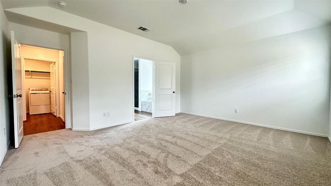 Unfurnished bedroom with visible vents, baseboards, washer / clothes dryer, carpet flooring, and vaulted ceiling | Image 8