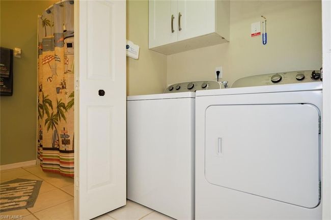 Clothes washing area with cabinets, separate washer and dryer, and light tile patterned flooring | Image 47