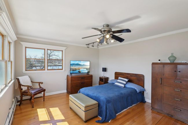 Bedroom featuring light wood-style floors, crown molding, baseboards, and a baseboard radiator | Image 20