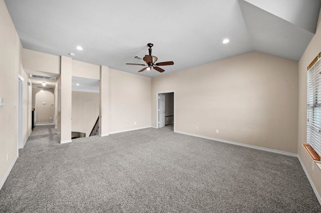 Unfurnished bedroom featuring vaulted ceiling, baseboards, arched walkways, visible vents, and light carpet | Image 25