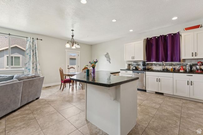 Kitchen with stainless steel dishwasher, a sink, decorative backsplash, a chandelier, and a center island | Image 4
