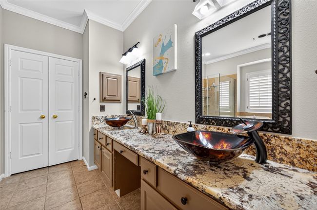 This bathroom features a dual vanity with ornate mirrors and vessel sinks on a granite countertop. It includes ample storage, modern fixtures, and a tiled floor, creating a stylish and functional space. | Image 30