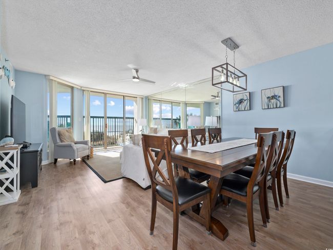 Dining area featuring baseboards, a textured ceiling, wood finished floors, and floor to ceiling windows | Image 10