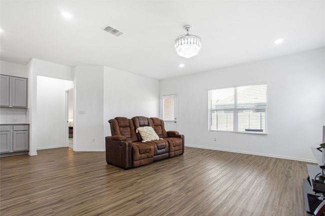 Living area with dark wood-style floors, a notable chandelier, visible vents, and recessed lighting | Image 6