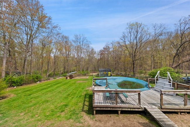 View of pool featuring a yard, a covered pool, a view of trees, and a wooden deck | Image 29
