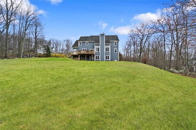 Rear view of property featuring a shingled roof, a wooden deck, a chimney, and a lawn | Image 38