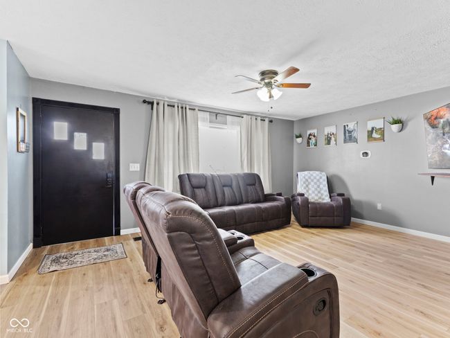 living room with a ceiling fan, baseboards, light wood finished floors, and a textured ceiling | Image 6