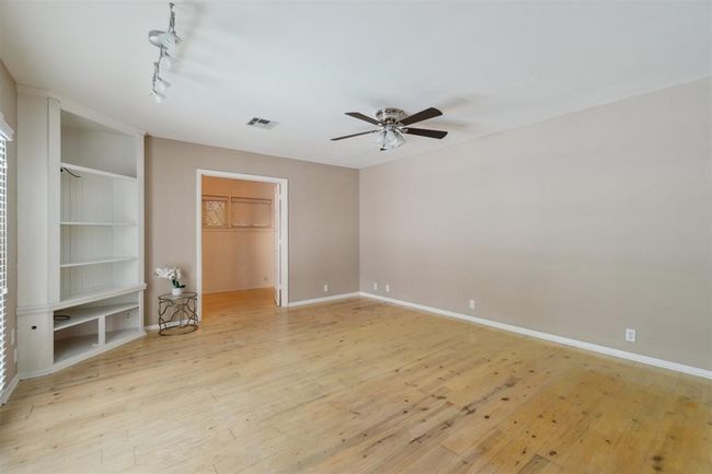 Unfurnished bedroom with light wood finished floors, a spacious closet, rail lighting, a closet, and a ceiling fan | Image 16