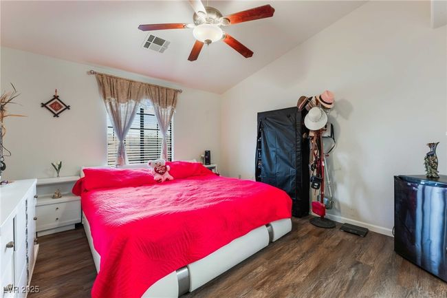 Bedroom with wood finished floors, vaulted ceiling, baseboards, visible vents, and a ceiling fan | Image 19