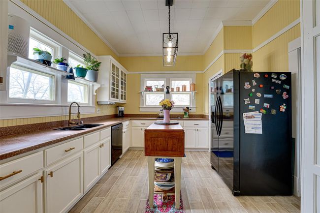 Kitchen with black appliances, ornamental molding, a sink, and white cabinetry | Image 13