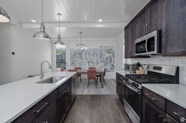 Kitchen featuring stainless steel appliances, a sink, light countertops, dark wood finished floors, and backsplash | Image 15