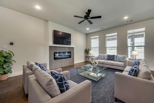 Living area featuring visible vents, baseboards, ceiling fan, a fireplace, and wood finished floors | Image 4
