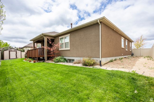 Back of property with a shed, an outdoor structure, a deck, and stucco siding | Image 43
