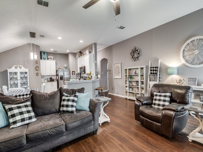 Living area with dark wood-style flooring, arched walkways, a ceiling fan, lofted ceiling, and baseboards | Image 10