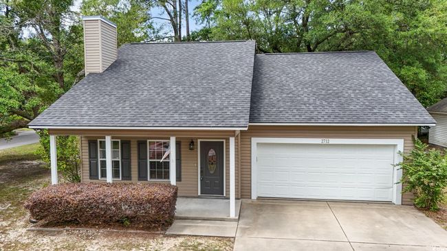 View of front facade with a shingled roof, a chimney, an attached garage, covered porch, and concrete driveway | Image 40