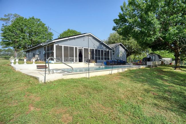 Rear view of property with a sunroom, a patio area, a shed, and an outdoor pool | Image 7