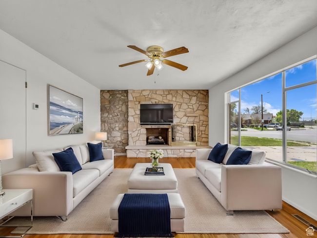 Living room with tons of light, ceiling fan, light wood finished floors, and a stone fireplace | Image 4