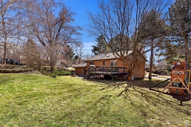 View of grassy yard featuring a deck and a playground | Image 35