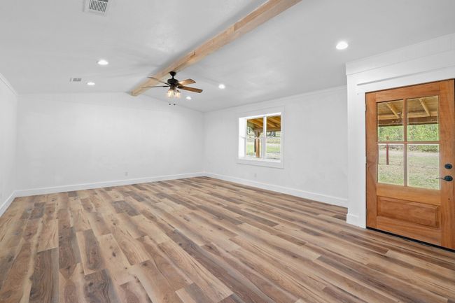 Unfurnished room featuring baseboards, a ceiling fan, light wood-style floors, visible vents, and vaulted ceiling with beams | Image 13