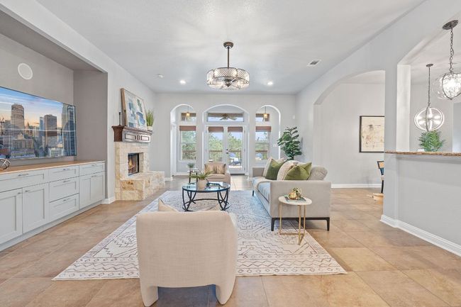 Living room with arched walkways, a chandelier, a fireplace, baseboards, and recessed lighting | Image 6