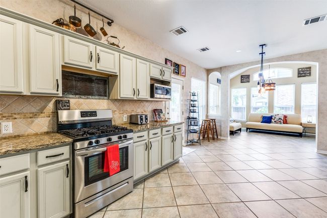 Kitchen with appliances with stainless steel finishes, arched walkways, backsplash, and light tile patterned floors | Image 8