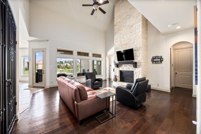 The main living area features an impressive two story fireplace and offers views of the back yard, pool, & community lake. | Image 10