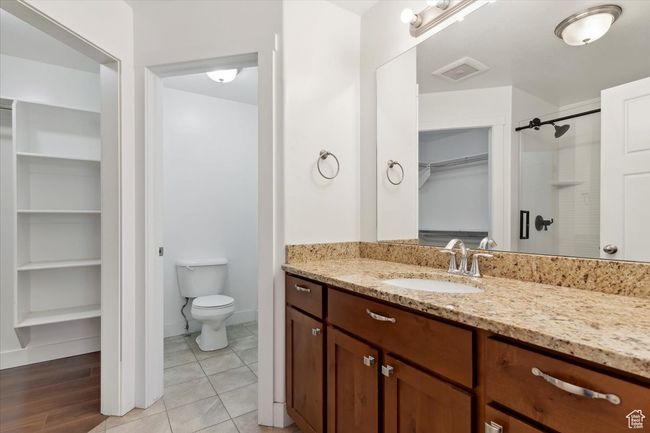 Full bathroom with vanity, a walk in closet, toilet, a shower, and baseboards | Image 18