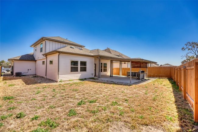 Back of house featuring a fenced backyard, a lawn, central air condition unit, a patio area, and board and batten siding | Image 39