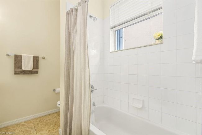 Full bathroom featuring baseboards, shower / tub combo with curtain, toilet, and tile patterned flooring | Image 24