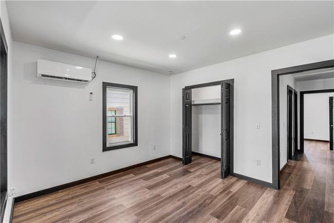 bedroom with a wall mounted air conditioner, wood finished floors, baseboards, recessed lighting, and a closet | Image 28