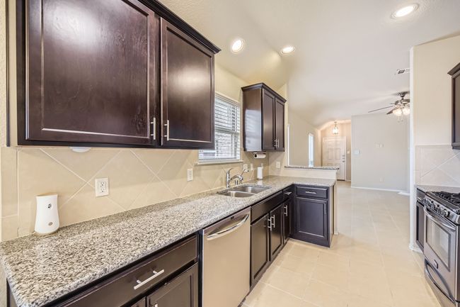 Kitchen featuring tasteful backsplash, stainless steel appliances, dark brown cabinetry, ceiling fan, and recessed lighting | Image 9